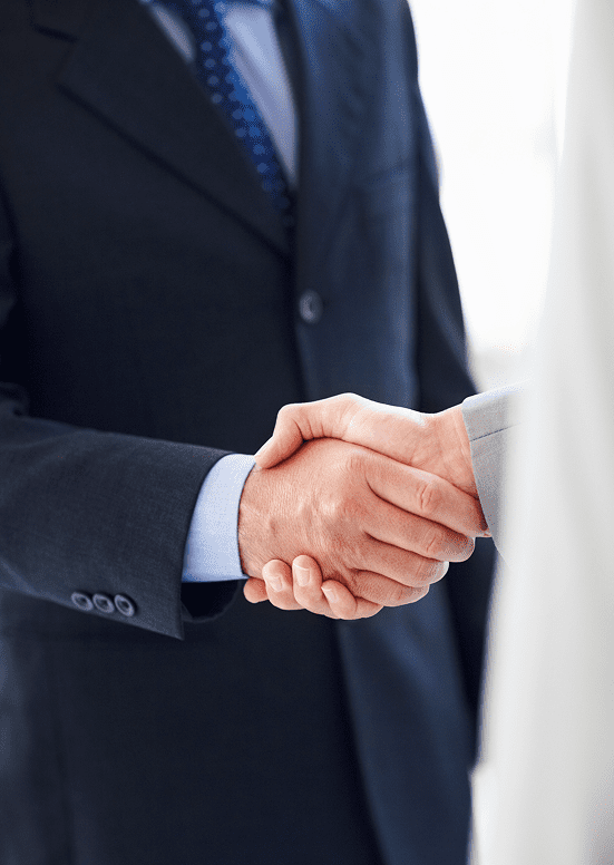 Two business professionals shaking hands in a formal setting.