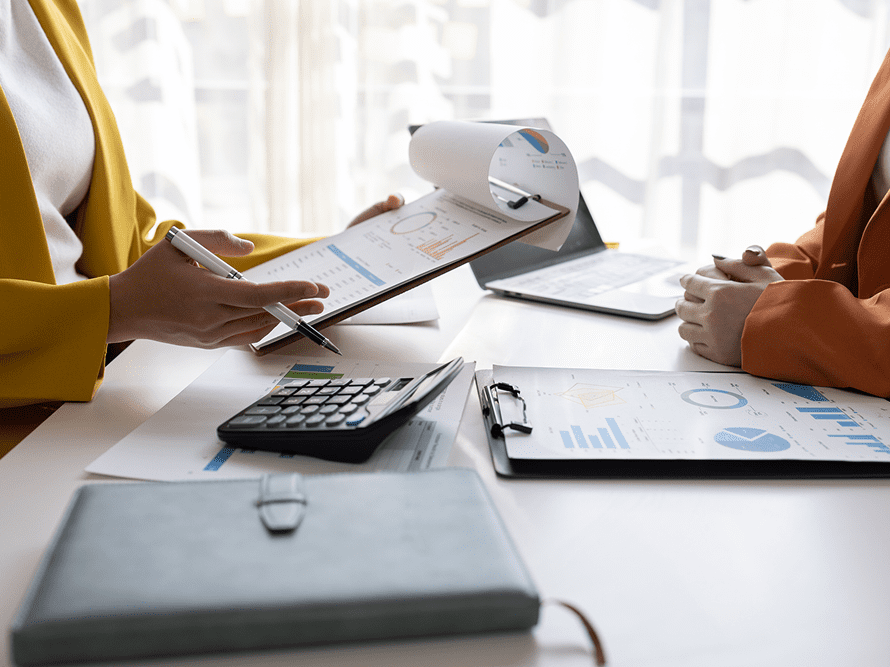 People discussing financial documents and calculations at a bright office desk.